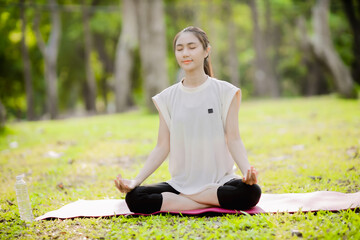 A enthusiastic Asian sports woman stopped after exercising at the garden, sitting on a exercise...