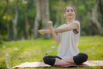 A enthusiastic Asian sports woman stopped after exercising at the garden, sitting on a exercise...