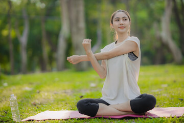 A enthusiastic Asian sports woman stopped after exercising at the garden, sitting on a exercise...