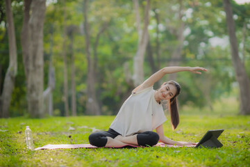A enthusiastic Asian sports woman stopped after exercising at the garden, sitting on a exercise...