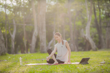 A enthusiastic Asian sports woman stopped after exercising at the garden, sitting on a exercise...