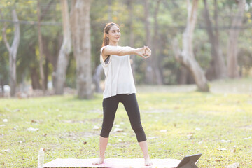 A enthusiastic Asian sports woman stopped after exercising at the garden, sitting on a exercise...