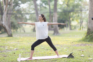 A enthusiastic Asian sports woman stopped after exercising at the garden, sitting on a exercise...