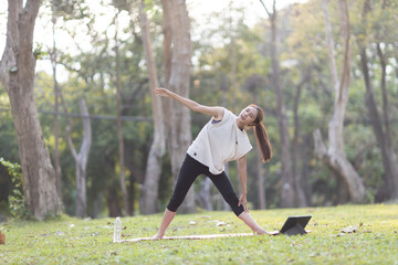 A enthusiastic Asian sports woman stopped after exercising at the garden, sitting on a exercise...