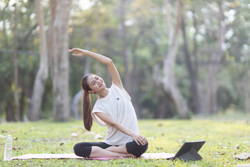 A enthusiastic Asian sports woman stopped after exercising at the garden, sitting on a exercise...