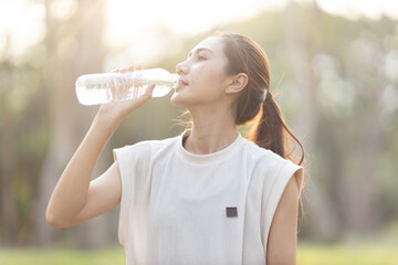 A enthusiastic Asian sports woman stopped after exercising at the garden, sitting on a exercise...