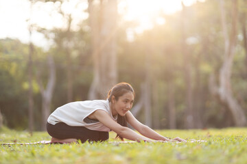 A enthusiastic Asian sports woman stopped after exercising at the garden, sitting on a exercise...