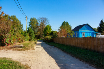 Fototapeta premium Village street with blue house in traditional style. Bolotskoye village, Zhukovsky district, Kaluga region, Russia