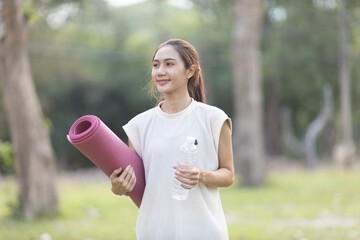 A enthusiastic Asian sports woman stopped after exercising at the garden, sitting on a exercise...