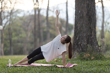 A enthusiastic Asian sports woman stopped after exercising at the garden, sitting on a exercise...