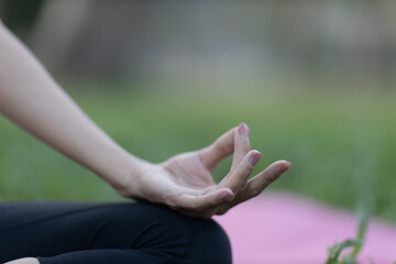 A enthusiastic Asian sports woman stopped after exercising at the garden, sitting on a exercise mat, inhaling deeply by closing her eyes. Sports and exercise regularly Health and health