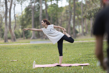 A enthusiastic Asian sports woman stopped after exercising at the garden, sitting on a exercise...