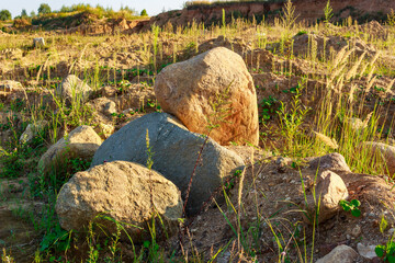 Rounded boulders lying on a sand quarry, glacial deposits of central Russia