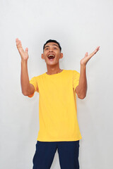 Surprised young Asian man in yellow shirt with open palms expresses joy