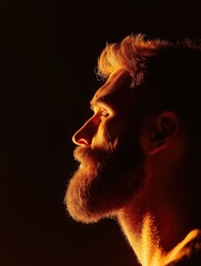 Close-up portrait of a man's face. the man is facing away from the camera, with his head turned slightly to the side. he has a beard and mustache, and his hair is styled in a short, spiky manner.
