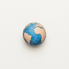 Fototapeta premium A small, hand-painted globe showing continents in earthy tones and oceans in blue, set against a plain background.