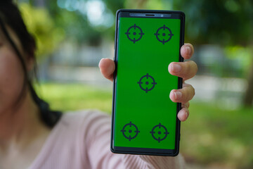 Person Holding Smartphone with Green Screen with Targeting Marks in a Park Blurred Green Trees Background