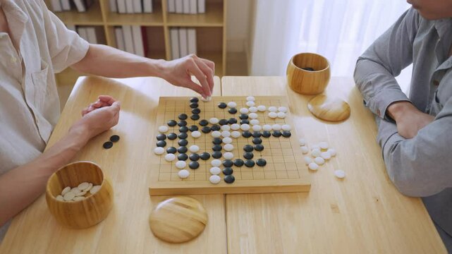 Close up of young men play board game Go during competition in community.