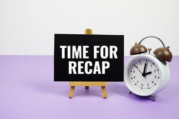 Time for Recap text on paper card with alarm clock on purple background