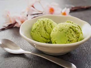 器に盛った抹茶のアイスクリームと桜の花