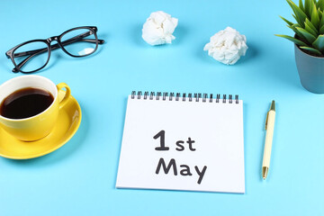 notepad with the words 1st may written on it next to a cup of coffee