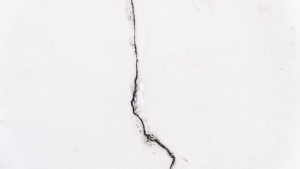 Close-up of a white wall with a detailed black crack, showing texture and damage