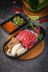traditional Asian beef dish, authentic Thai cuisine,, Authentic Thai raw beef salad set with spicy dipping sauces, fresh herbs, and traditional Asian ingredients on woven rattan tray