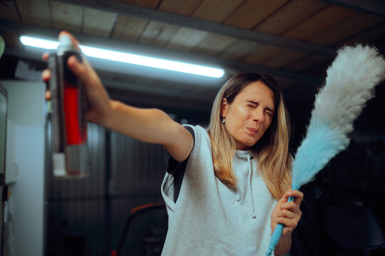 Woman Cleaning and Holding Insect Spray in a Warehouse. Stressed lady killing insects with pesticide while cleaning the dust 
