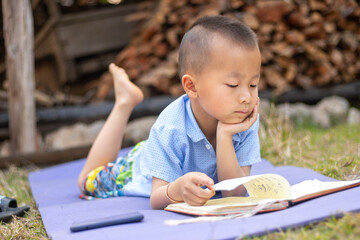 A young boy reading and do homework outdoor