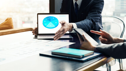 A group of business people having a meeting while looking at the screens of a laptop and tablet PC