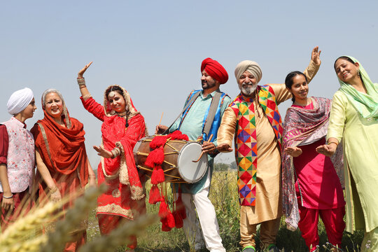 Punjab people celebrating Baisakhi or vaisakhi festival in agriculture field and doing bhangra dance. Punjabi sikh family enjoying festive season together, Culture of india.