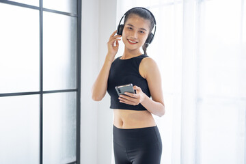 Fitness asian woman using smart phone and headphones Enjoy listening to music. Female with headphones smart phone after workout