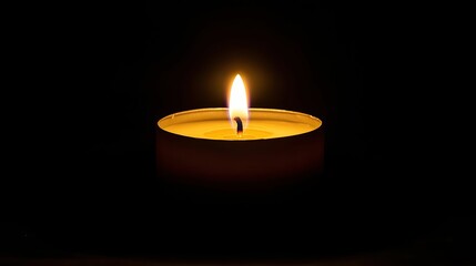 Burning candle in dark; small, round container.