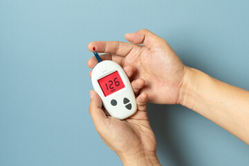 Woman's hands checking diabetes and hyperglycemia with digital blood sugar meter. Healthcare and...