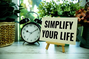 Simplify Your Life text  motivational and inspiration quote with alarm clock on wooden background