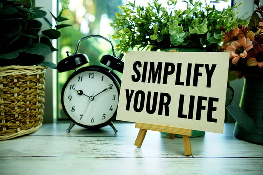 Simplify Your Life text  motivational and inspiration quote with alarm clock on wooden background