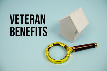 Veteran Benefits text with White Model House and magnifying glass on blue background
