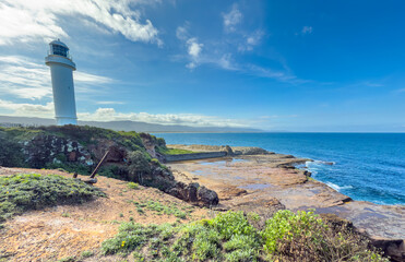 A view of Flagstaff Point Lighthouse, Wollongong, New South Wales, Australia with cliffs and exposed tidal rocks beneath