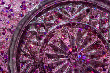 Full frame macro abstract texture background of a crystal glass coaster on sparkling multicolor pink glitter with copy space
