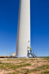 Obraz premium Female engineer working at the base of a wind turbine on a clear day