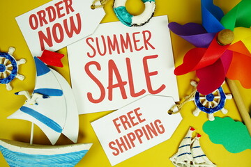 Summer Sale text on paper card with marine items decorative top view on yellow background