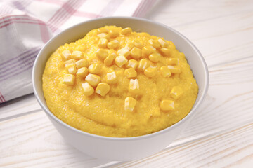 Delicious corn porridge in a bowl on a white wooden table.