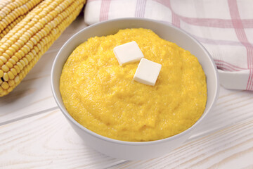 Delicious corn porridge in a bowl on a white wooden table.