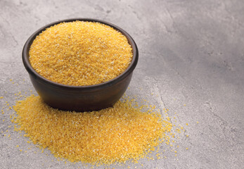 Raw cornmeal in a bowl on a gray tiled table