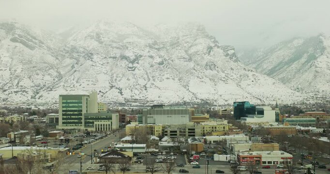 Beautiful aerial shot over Provo, Utah city with distant snow covered rocky mountain - wide