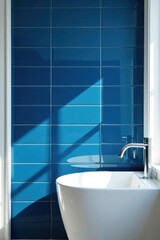 Modern bathroom design featuring a sleek, white vessel sink against a vibrant, azure tiled wall, bathed in sunlight.