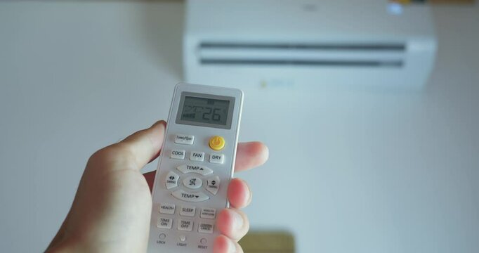 Person pressing remote control air conditioner activates bringing relief in hot climate Cooling air conditioner becomes indispensable in summer. Comfort at home with air conditioner ensures ease.
