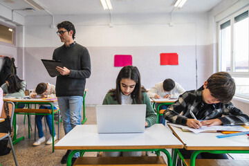 Teacher supervising students taking exam in classroom
