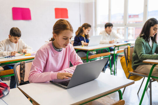 Students using laptops and taking notes in classroom