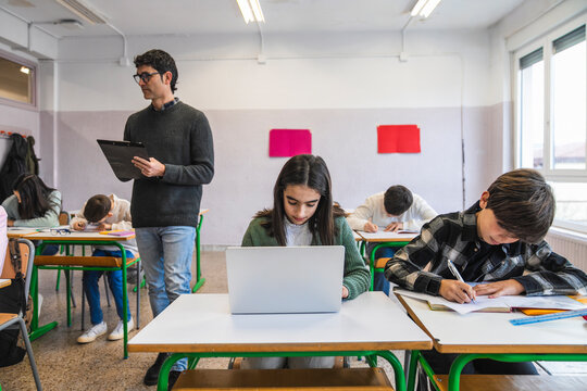 Teacher supervising students taking exam in classroom